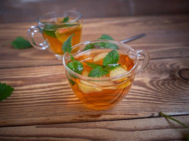 Cam bardağı sıcak ahşap zemin ile elma ve melissa ile çay