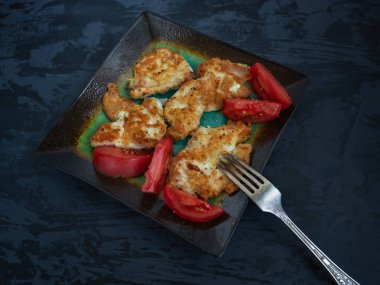 Kahvaltı kızarmış balık ve seramik tabak yakın çekim üzerinde kırmızı domates. Koyu ahşap arka plan.