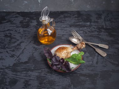 Yemek tavuk budu, taze salata, roka ve fesleğen. Bir cam tencerede sos. Koyu arka plan.