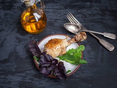 Yemek tavuk budu, taze salata, roka ve fesleğen. Bir cam tencerede sos. Koyu arka plan.