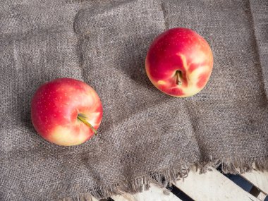 İki kırmızı ve sarı elma bir çuval bezi peçete ve bir ahşap kutu. Yakın çekim. Yukarıdan görüntüleyin. Defocused