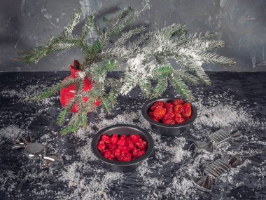 Set kırmızı kurutulmuş meyveler siyah vazo içinde bir köknar dalı karanlık bir arka plan üzerinde kırmızı bir vazo. Bir saçılma kar. Noel kartı. kızılcık, kiraz
