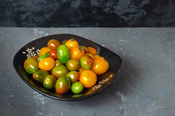 Kırmızı ve yeşil küçük domates gri arka plan üstten görünüm üzerinde tam bir fincan