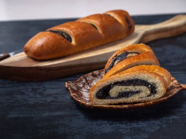 Dekoratif ahşap tepsi ve dekoratif tabak içinde karanlık bir arka plan üzerinde kesme adet haşhaş alır. Yakın çekim. Mutfak bıçağı.