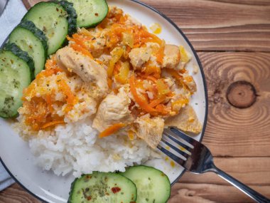 Kahvaltı tavuk ve pirinç, hafif ahşap arka plan üzerinde taze salatalık dilimleri