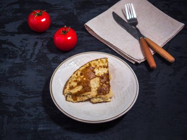 Omlet ve domates, çatal bıçak takımı karanlık bir arka plan üzerinde hafif kahvaltı