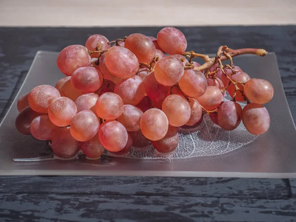 Een Borstel Roze Druiven Een Glasplaat Donkere Achtergrond — Stockfoto