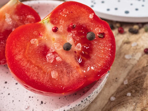 Half a tomato sprinkled with salt and pepper close up