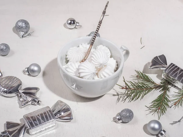Tasse blanche avec biscuit bisa, cuillère à café en argent aux couleurs vives. Jouets de Noël et un brin d'épinette sur une table blanche — Photo