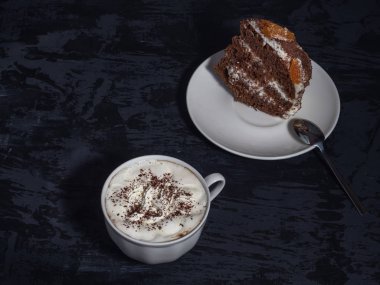 Ev yapımı kek ve kahve krem ve karanlık bir arka plan üzerine rendelenmiş çikolata ile bir parça. Beyaz yemekleri.