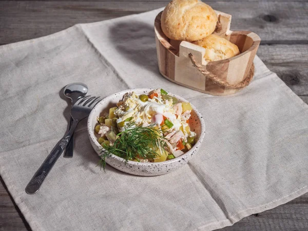 Olivier salata, bir kosinochka içinde yuvarlak çörekler keten peçeteye yanında bir tabak çatal bıçak takımı yalan