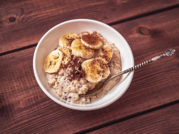 Ein gesundes Frühstück mit Haferflocken, Bananenscheiben und Schokoladenchips ist eine köstliche Ergänzung zum Haferbrei. verschwommener Fokus. — Stockfoto