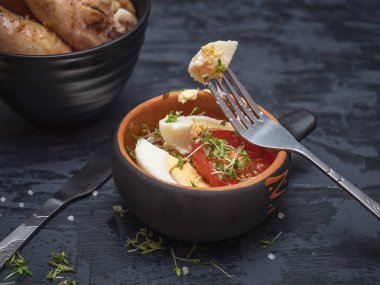 Yemek pişmiş tavuk ızgara, sebze ve yumurta salatası, siyah çanak çömlek ve çatal bıçak takımı. Tuz shaker ahşap kaba tuz döktüm. Yan görünüm.