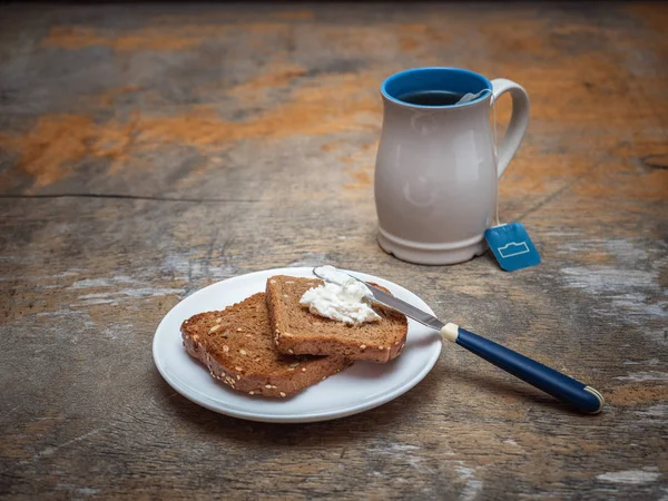 A high bright mug with packaged tea, toasts on a saucer on the old table.