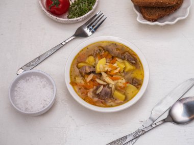 Türkiye sebze ve bir derin seramik kase karanlık ekmek ile öğle yemeği için makarna çorbası. Çorba kaşığı ve rustik masada tuz kaba tuz.