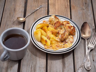 Fırında patates köfte, çay bir alüminyum kupa ve tahta tablo ve tablo gümüş çatal bıçak takımı ile Kahvaltı