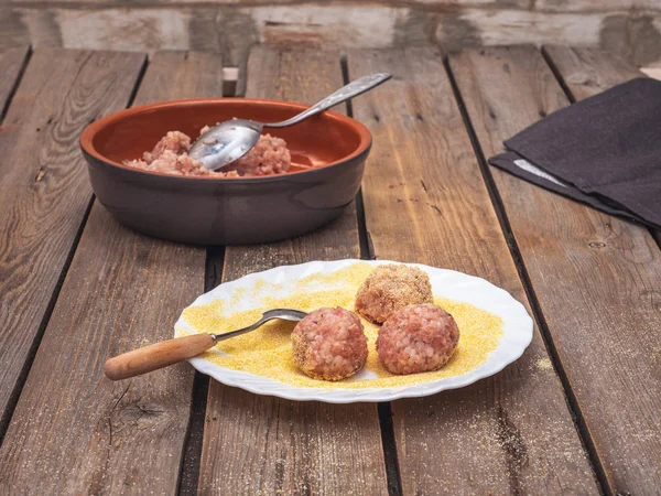 Cooking meatballs from dietary turkey meat. Minced raw in a deep ceramic plate. Composition on a rustic wooden board table.