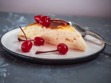 Bir çay kaşığı, güveç seramik bir daire üzerinde süzme peynir güveç bölümünü konserve kiraz ile dekore edilmiştir.