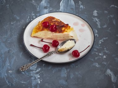 Seramik bir uçan daire dekore edilmiş konserve kiraz ile üzerinde süzme peynir güveç parça dilimlenmiş, gri bir arka plan üzerinde çok yakın mesafeden vurdu