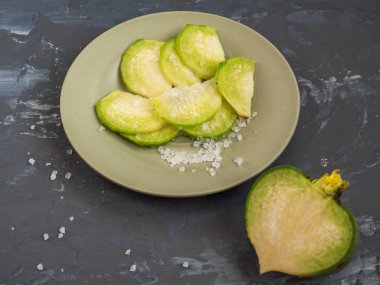 yeşil turp dilimlenmiş ve kaba tuz ile serpilir bir seramik plaka oliskovogo renk yatıyor