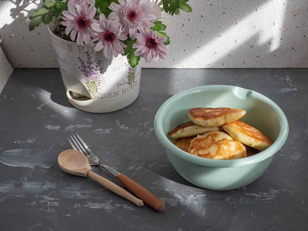 Zelfgemaakte Cheesecakes in een diepe kop met houten bestek op een grijze achtergrond, chrysant op de achtergrond, grijs gevlekte achtergrond. — Stockfoto