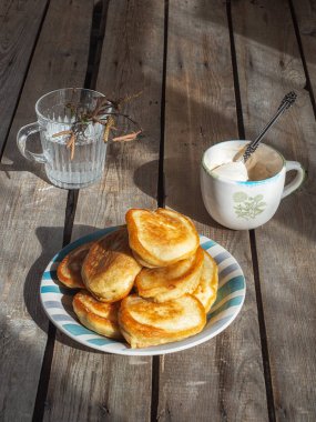 Bir tabak taze pişmiş krep bir yığın yatıyordu. Huş ağacı küçük beyaz bir sürahi.