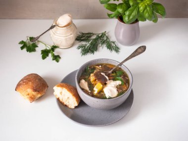 Ekşi krema ve baharatlı otlar, beyaz bir masada ekmek kırık parçaları ile derin bir tabakta lezzetli mantar çorbası