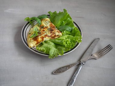 Marul yapraklarının üzerinde yatan çırpılmış yumurtadan hafif kahvaltı. Mavi tabakta marul servis.