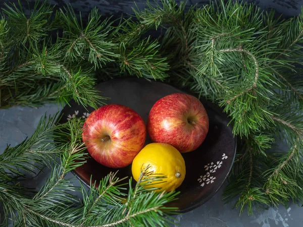 Pommes rouges dans un vase en céramique noire, autour des branches vertes du cèdre — Photo