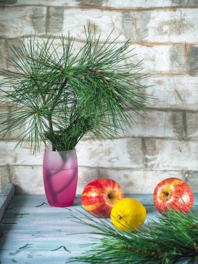 Ahşap bir tahta arka plan üzerinde Elma ve limon, bir waddling çam dalı arka planda