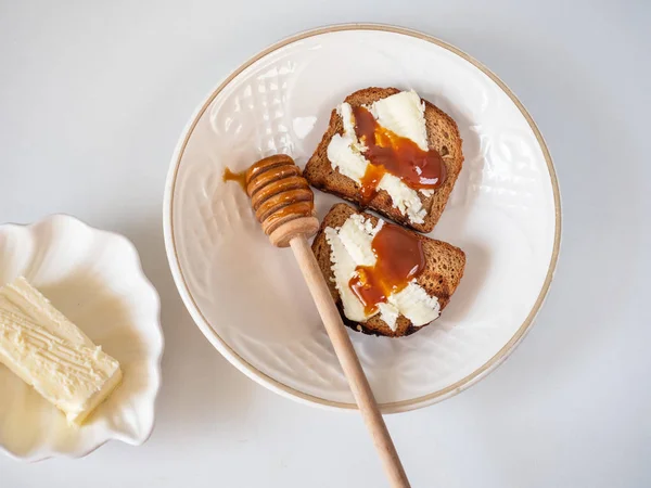 Sandwiches dulces con mantequilla y miel en un plato blanco con una cuchara de madera para miel — Foto de Stock