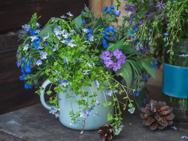 Razgotrave en una taza pequeña, un encantador ramo de verano de flores azules Conos de pino, disparados de cerca — Foto de Stock