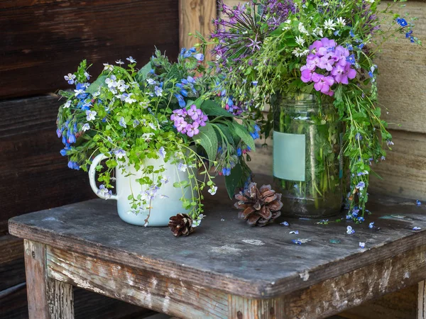 Bouquets of colorful field flowers. pine cones on an old stool on a rustic porch — Stock Photo, Image