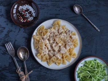 Krem soslu makarna ve sarımsak, gri bir arka plan üzerinde yuvarlak tabaklarda taze rendelenmiş salatalık salatası, çatal ve kaşık, küçük bir tabak üzerinde baharatlar, Top View