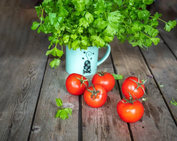 Vegetales sobre una mesa de madera sin pintar. Tomates rojos y un manojo de perejil en una taza de cerámica — Foto de Stock
