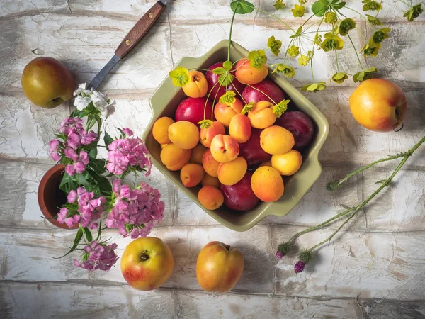 Fruit set of fresh fruits in a ceramic square plate, a bouquet of forest carnations in a small vase, shot a supernova