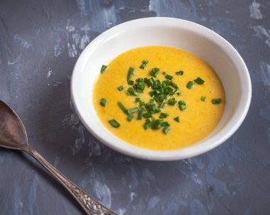 Sebze ve peynir ile patates püresi çorbası yeşil soğan, gri bir arka planda bir çorba kaşığı serpilir