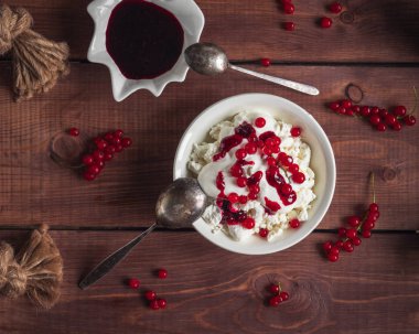 Ekşi Krem ile süzme peynir hafif bir kahvaltı, kırmızı frenk üzümü çilek ve reçel, bir kaşık, ve ahşap bir tepsi üzerinde beyaz krem kasede frenk üzümü reçel