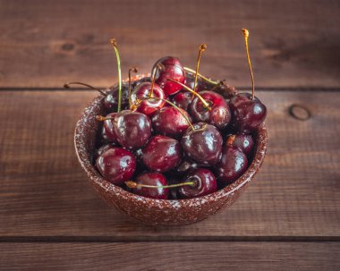 Ahşap bir tepsi üzerinde derin bir seramik MissK olgun tatlı kiraz