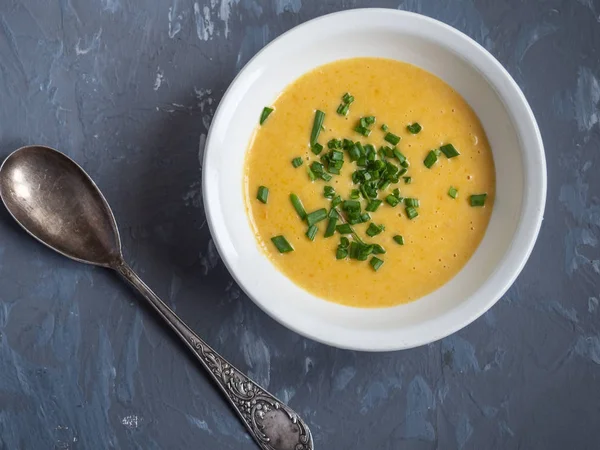 Sebze ve peynir ile patates püresi çorbası yeşil soğan, gri bir arka planda bir çorba kaşığı serpilir