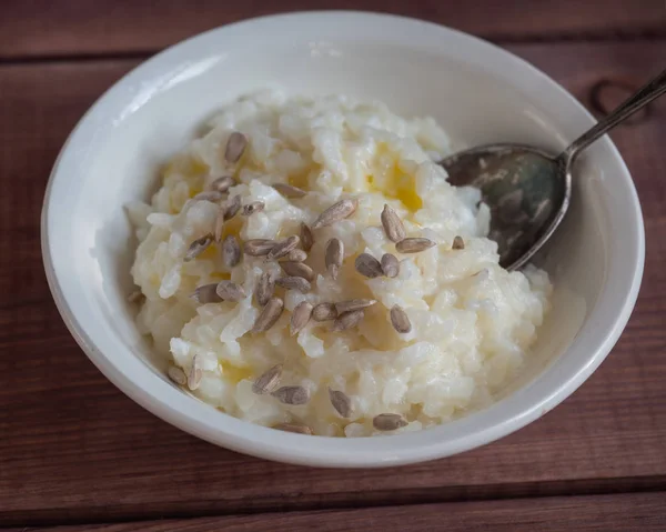 Milk rice porridge with sunflower seeds in a deep white plate