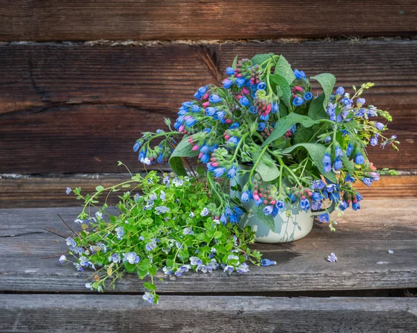 Bouquet of wild flowers in an enamel mug on the porch of a village house — Stock Photo, Image