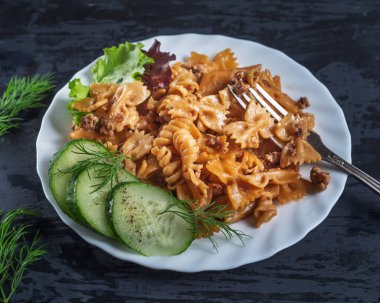 Besleyici kahvaltı. Beyaz bir tabak, bir yemek çatalı üzerinde hindi kıyma, salatalık dilimleri ve dereotu dilimleri ile koyu un ezmesi. Koyu ahşap arka planda servis yapın.