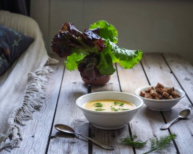 Peynir çorbası ve koyu ekmek kruton, ahşap bir masa üzerinde duran seramik cam yaprak salatası