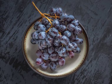 Siyah üzüm bir fincan koyu ahşap bir masa üzerinde duruyor