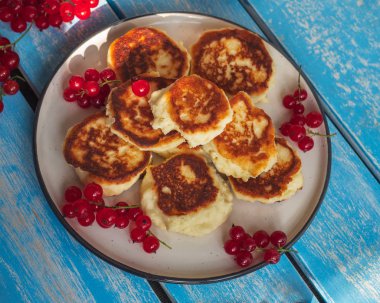 Kırmızı frenk üzümü sprigs ile yuvarlak bir tabak ta ev yapımı cheesecakes