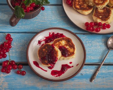 Reçel ve kırmızı frenk üzümü sprigs ile iki tabak üzerinde ev yapımı cheesecakes