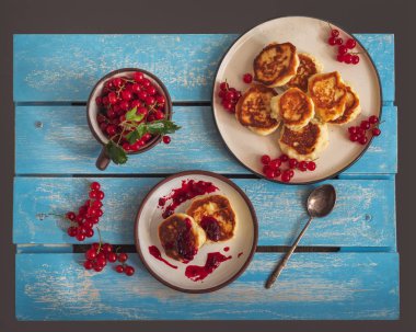 Reçel ve kırmızı frenk üzümü, frenk üzümü ile bir kupa sprigs ile iki tabak üzerinde ev yapımı cheesecakes