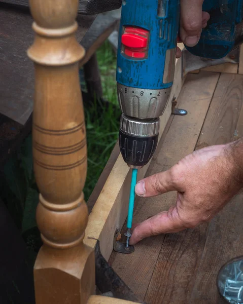 Men\'s hands at work with a drill to repair the table
