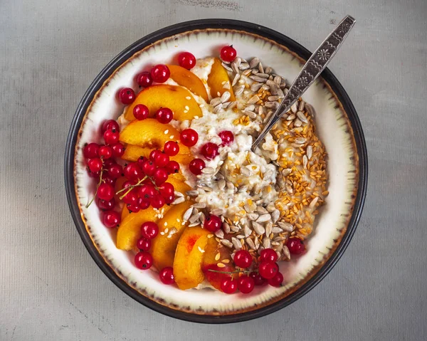 Leckeres und gesundes Fitness-Frühstück aus Haferflocken mit Beeren, Früchten und Müsli in einem tiefen Teller und Löffel auf grauem Hintergrund — Stockfoto